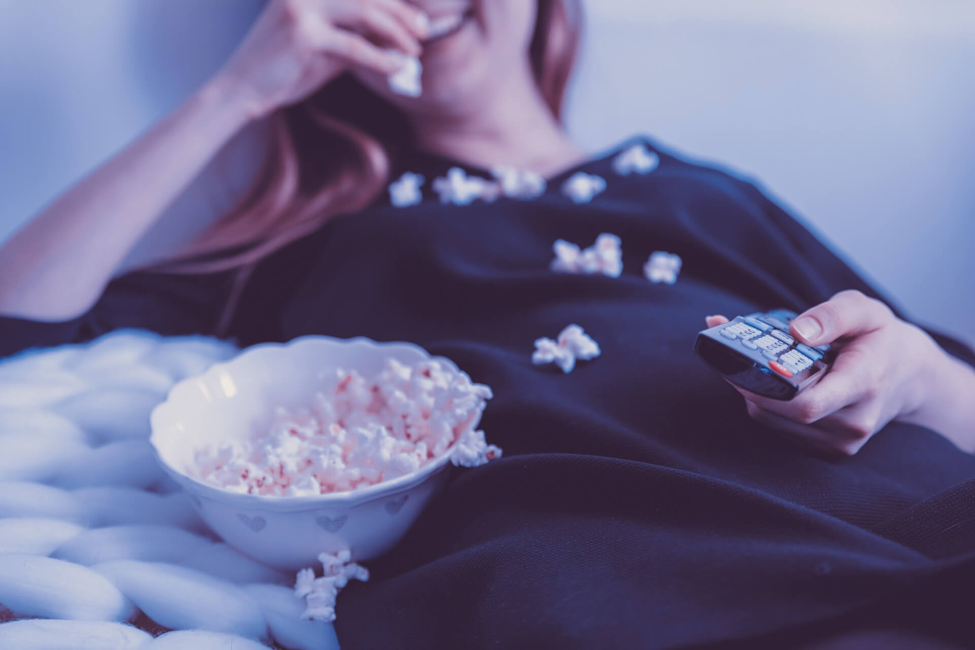 woman eating popcorn in front of television advertising