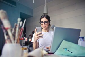 woman looking at her smart phone at home office desk